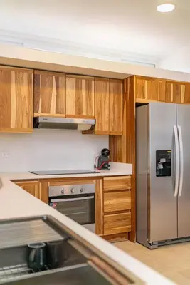 a kitchen with wooden cabinets and a stainless steel refrigerator at Hermosa Palms, Casa Lorenzo Beach Front Club House in Playa Hermosa