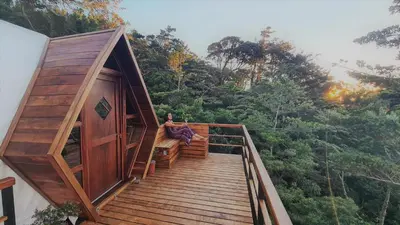 a person sitting on the stairs of a tree house at NATURAVE - Into the woods - Mountain cabins in Monteverde Costa Rica