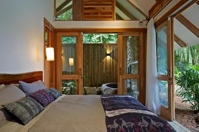 a bedroom with a bed in a room with glass doors at Casa Ananda a Bali Inspired Home in Nosara