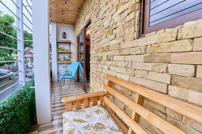 a porch with a wooden bench on a brick wall at Apartaestudio La Capital in San José