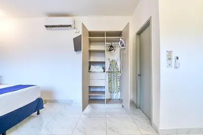 a room with a bed and a closet with a surfboard at Apartaestudio La Capital in San José