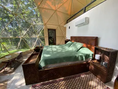 a bedroom with a bed in a room with large windows at Way To Heaven Glamping in Monteverde Costa Rica