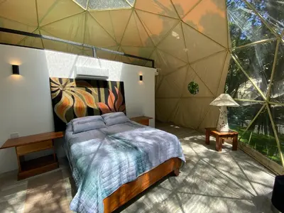 a bedroom with a bed in a room with a large window at Way To Heaven Glamping in Monteverde Costa Rica