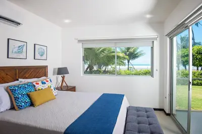 a bedroom with a bed and a large window at Beachfront Condo - your Oasis with pool and Wi-Fi in Bejuco