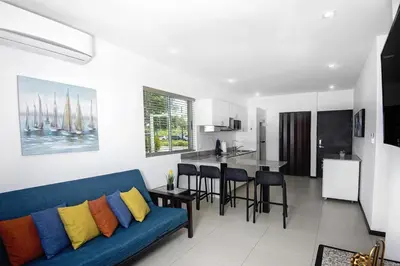 a living room with a blue couch and a kitchen at Beachfront Condo - your Oasis with pool and Wi-Fi in Bejuco