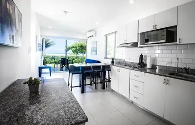 a kitchen with white cabinets and a table with chairs at Beachfront Condo - your Oasis with pool and Wi-Fi in Bejuco