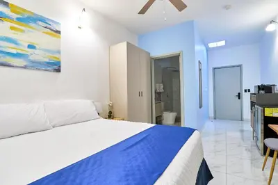 a white bedroom with a bed and a bathroom at Apartaestudios La capital in San José