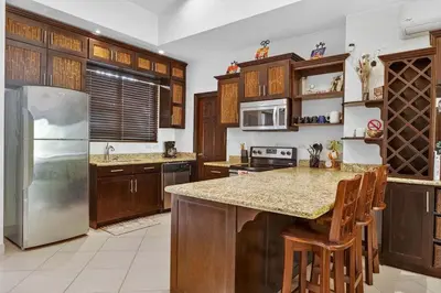 a kitchen with wooden cabinets and a stainless steel refrigerator at Roca Blanca -Private Pool- Near To Conchal & Flamingo Beach in Brasilito