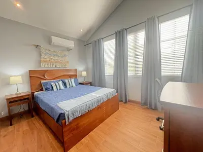 a bedroom with a wooden bed with blue sheets and windows at Casa Mariposa - villa with infinity pool, near beach in Brasilito