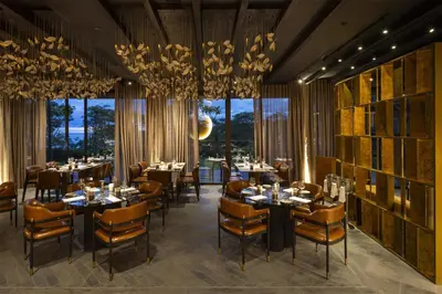 a dining room with tables and chairs and chandeliers at Waldorf Astoria Costa Rica Punta Cacique in Playa Hermosa