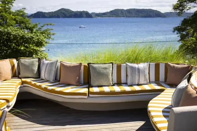 a yellow and white couch with pillows on a deck at Waldorf Astoria Costa Rica Punta Cacique in Playa Hermosa