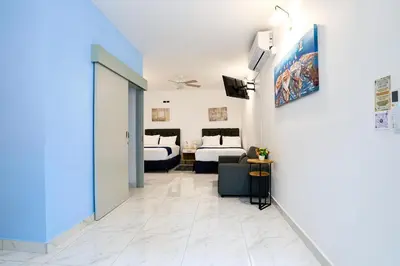 a hotel room with two beds and a living room at Apartaestudios la capital in San José