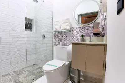 a white bathroom with a toilet and a mirror at Apartaestudios la capital in San José