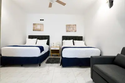 two beds in a room with a couch at Apartaestudios la capital in San José