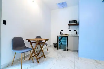 a small kitchen with two chairs and a table in a room at Apartaestudios la capital in San José