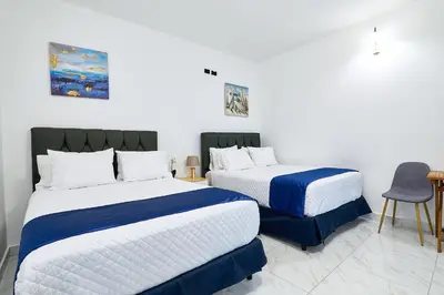 a bedroom with two beds and a chair at Apartaestudio la capital in San José