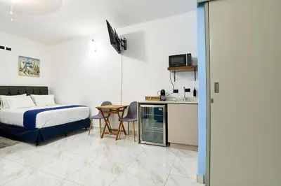 a bedroom with a bed and a table and a kitchen at Apartaestudio la capital in San José