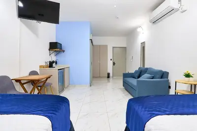 a living room with two beds and a blue couch at Apartaestudio la capital in San José