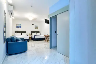 a living room with a blue couch and a bedroom at Apartaestudio la capital in San José