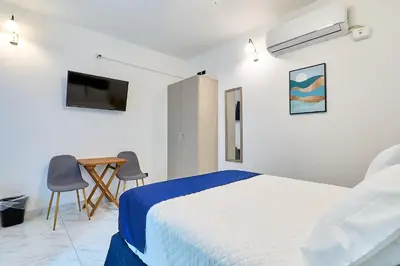 a white bedroom with a bed and a table and chairs at #5 Apartaestudio la capital in San José