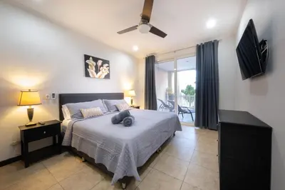 a bedroom with a large bed and a balcony at The Palms Ocean Club Resort in Jacó