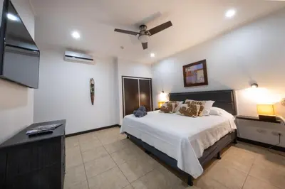 a bedroom with a bed and a ceiling fan at The Palms Ocean Club Resort in Jacó