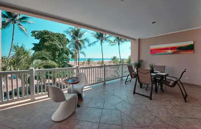 a balcony with a view of the ocean and palm trees at The Palms Ocean Club Resort in Jacó