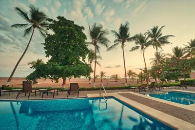 a swimming pool with chairs and palm trees on the beach at The Palms Ocean Club Resort in Jacó