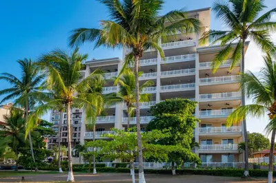 an apartment building with palm trees in front of it at The Palms Ocean Club Resort in Jacó