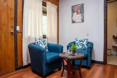 a living room with two blue chairs and a table at Tierra Buena Countryside Hotel in Monteverde Costa Rica