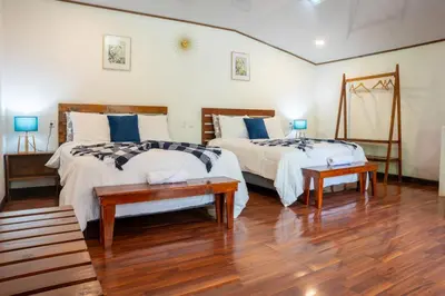 two beds in a room with wooden floors at Tierra Buena Countryside Hotel in Monteverde Costa Rica
