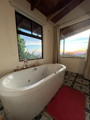 a white bath tub in a bathroom with a window at Villas Flakis, Vela in Monteverde Costa Rica