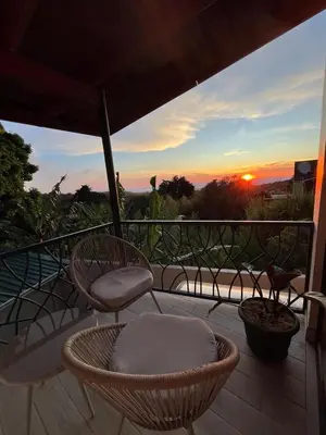 a balcony with chairs and a sunset in the background at Villas Flakis, Vela in Monteverde Costa Rica