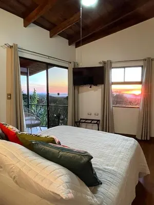 a bedroom with a bed and a large window with a view at Villas Flakis, Vela in Monteverde Costa Rica