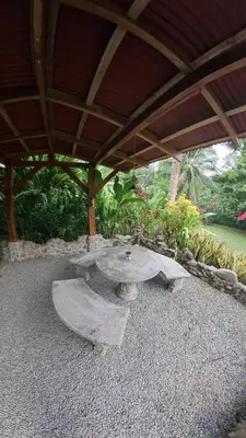 a patio with a stone table under a roof at Casitas Del Rio Riverfront Nature Lodge in Uvita