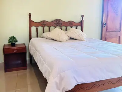 a bed with two pillows on it with a table at Los Tucanes Lodging in El Castillo de La Fortuna