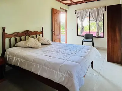 a bedroom with a bed and a chair and a window at Los Tucanes Lodging in El Castillo de La Fortuna