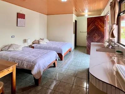 a hotel room with two beds and a sink at Los Tucanes Lodging in El Castillo de La Fortuna