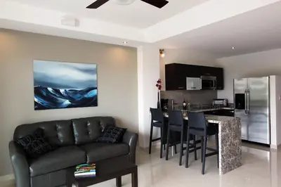 a living room with a couch and a kitchen at Oceano Boutique Hotel & Bistró in Jacó