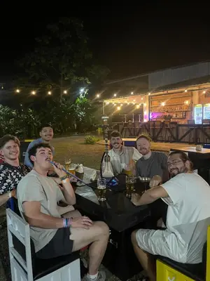a group of people sitting around a table at night at Asha Hostel in Fortuna