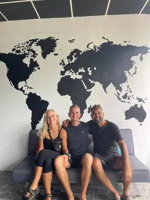 three people sitting on a couch in front of a world map at Asha Hostel in Fortuna