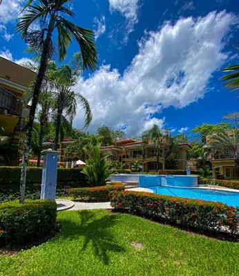 a resort with a swimming pool and palm trees at Espacioso Condominio en Pacific Sun in Jacó