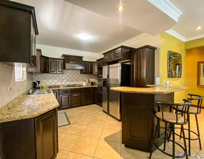 a large kitchen with wooden cabinets and counters and bar stools at Espacioso Condominio en Pacific Sun in Jacó