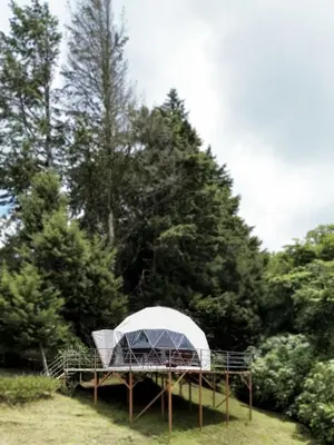 a white tent on a platform in a field with trees at Green Noise Glamping in Fraijanes