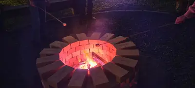 a brick fire pit with a person holding a stick at Casa Arthémis - Rainforest Lodge in Guápiles