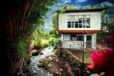 a house on a hill next to a river at Rainforest Cabin in Escazu in Escazu