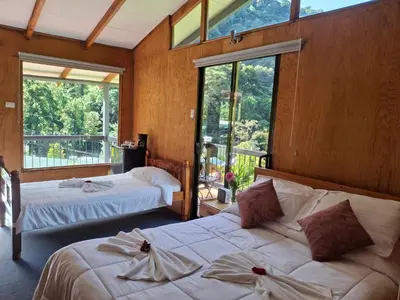two beds in a room with large windows at Cabaña Tangara in San Gerardo de Dota