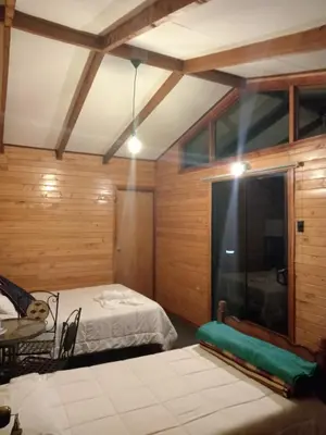 a bedroom with a bed and a table and a window at Cabaña Tangara in San Gerardo de Dota