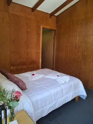a bedroom with a large white bed with wooden walls at Cabaña Tangara in San Gerardo de Dota