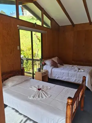 two beds in a room with a window at Cabaña Tangara in San Gerardo de Dota